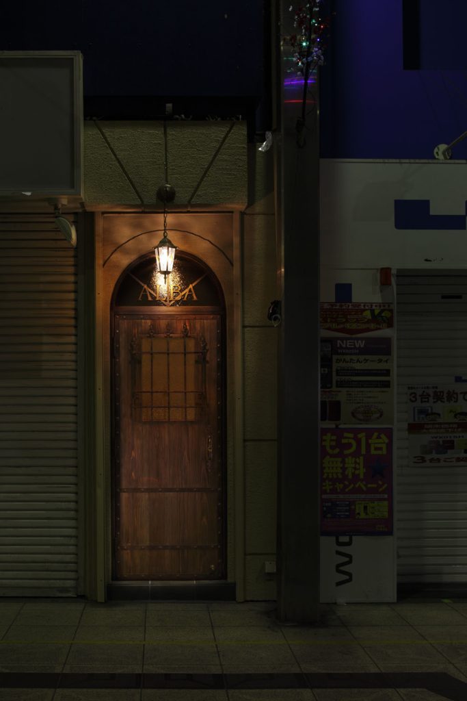 大阪・天満のBAR ALBAの入り口。温かみのあるランプが灯る隠れ家的なバーの扉
Entrance of BAR ALBA in Osaka Tenma, a hidden gem with a warm-lit wooden door.