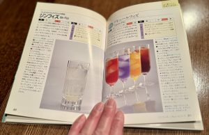 カクテルブックの見開きページ。左にはジンフィズのレシピと透明なカクテルの写真、右には色鮮やかなリキュールフィズのカクテルが並ぶ写真が掲載されている。