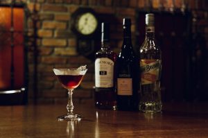 BAR ALBA（バー・アルバ）オリジナルカクテル『ダスク・アイランド』の写真。アイラモルト、シェリー、カカオリキュールのボトルと並ぶことで、味の構成が伝わるカクテル紹介に最適なカット。