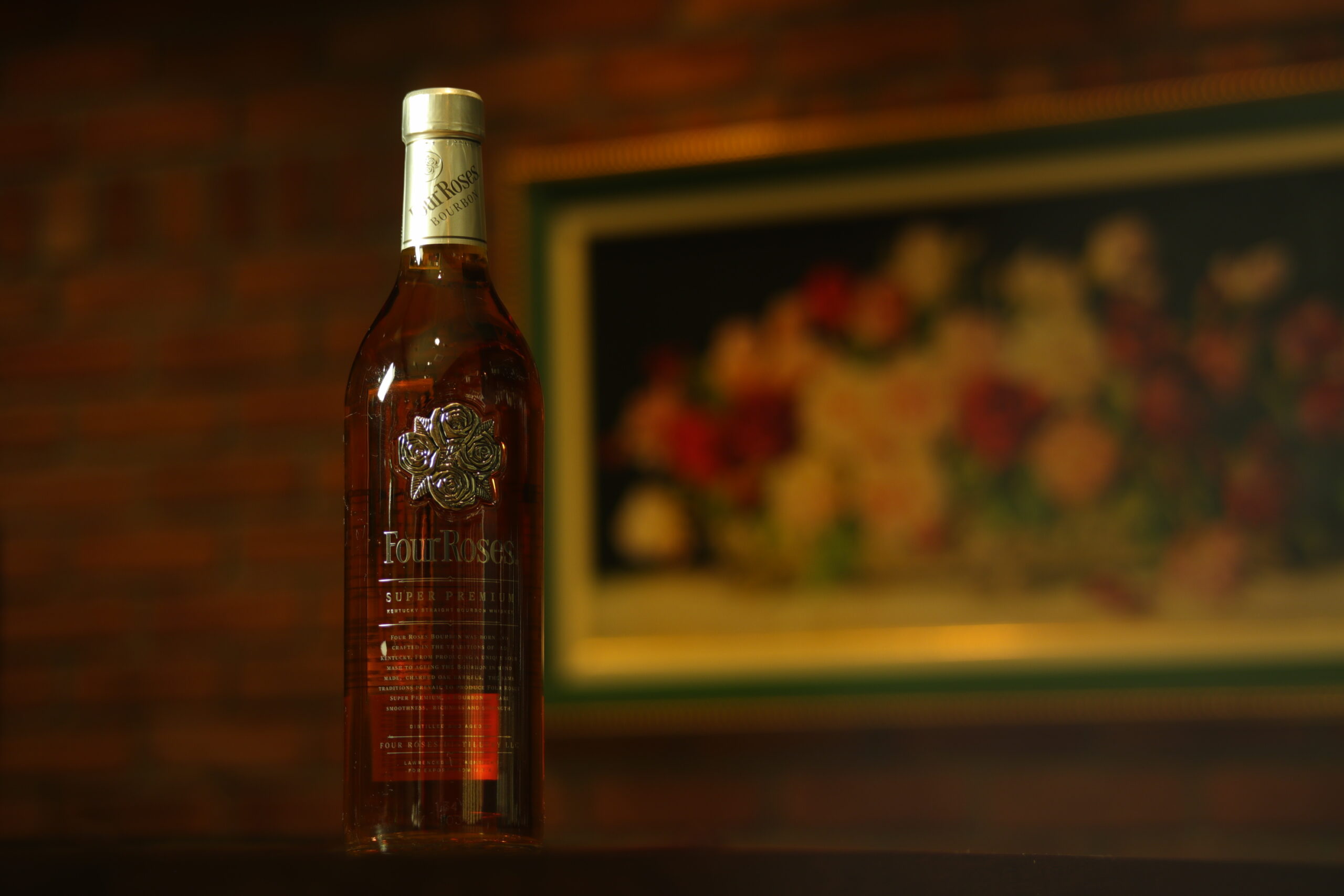 フォアローゼズ・プラチナのボトル。温かい灯りの店内で撮影された、琥珀色が美しいバーボン。 Four Roses Platinum bottle photographed in warm bar lighting, showing the rich amber color of the bourbon.